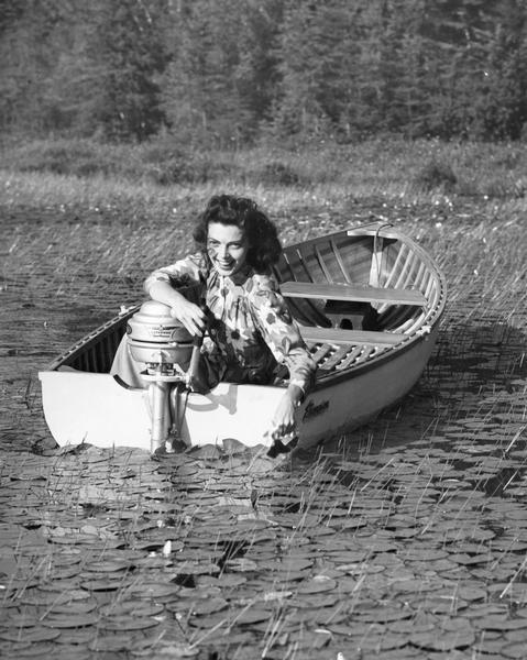 A woman in a boat is smiling into the camera in an ad for an Evinrude motor.