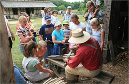 A group of school children surround a shingle maker.