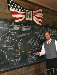A teacher point to a drawing of Wisconsin on the blackboard.