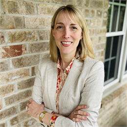 Photograph of Kristen Leffelman, a blonde woman wearing a floral shirt and beige blazer