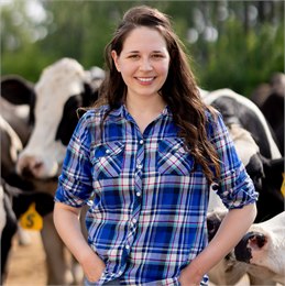 Photo of Mary Lewandowski smiling, pictured in front of her dairy cows.