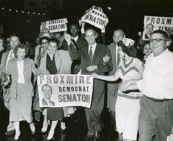William Proxmire celebrates with his wife Ellen (to Proxmire's right), and a crowd of supporters in Milwaukee after his victory in a special election after the death of Senator Joseph R. McCarthy.