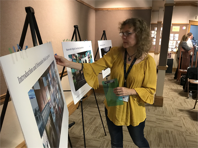 A guest places her green preference sticker onto a new museum exhibit concept rendering.