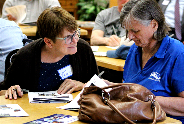 Lynn Gevens laughs with a fellow guest as they review a packet of new museum concept exhibit design renderings during the Wisconsin Historical Society's "Share Your Voice" listening session May 29, 2019 in Cameron.