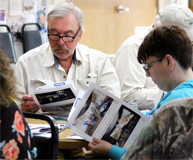 Bob Schutz (left) and Betty Anne Benes (right) examine packets of concept exhibit design renderings during the Wisconsin Historical Society's "Share Your Voice" new museum listening session for Barron County residents May 29, 2019 in Cameron.