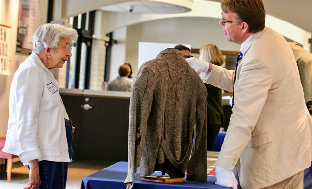 A guest listens as Matt Blessing (right) of the Wisconsin Historical Society talks about a rare artifact from the Society's collections that was on display: A sweater worn by a Holocaust survivor while he was a prisoner at Auschwitz.