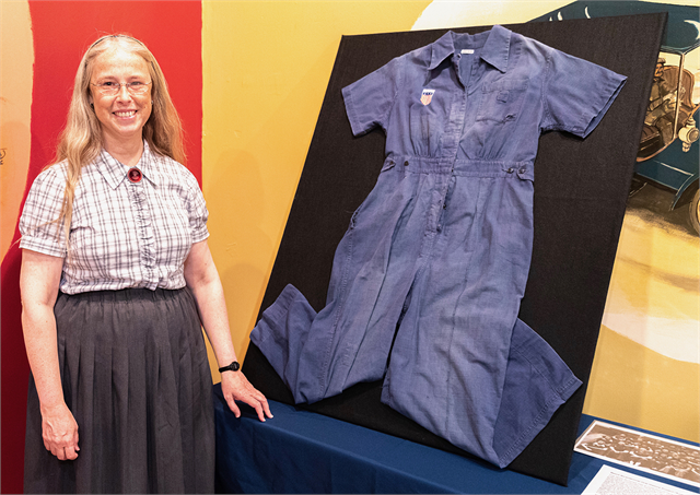Wisconsin Historical Society Outreach Curator Tamara Funk poses with the set of coveralls worn in 1943 by a real-life "Rosie the Riveter" who worked in Beloit's Fairbanks Morse factory.