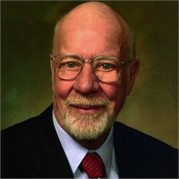 Headshot of Senator Fred A. Risser. He is pictured wearing glasses, a black suit with a blue collared shirt, and a red tie.