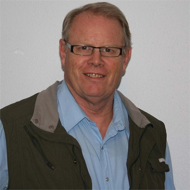 Photo portrait of Robert Silbernagel wearing a green vest and blue button-down shirt