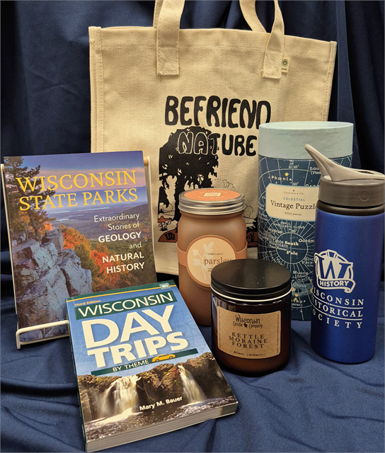 Gift basket includes Wisconsin State Parks and Day Trips by Theme guidebooks, two scented candles (Parsley and Kettle Moraine Forest), a celestial-themed 1000-piece puzzle, stainless steel water bottle, and a “Befriend Nature” canvas tote.