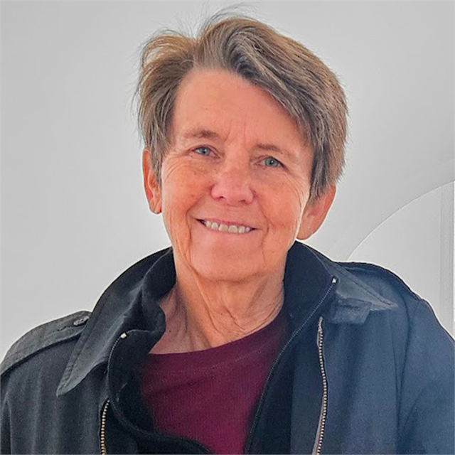 Author Margaret Mooney pictured smiling, wearing a black jacket and pink shirt.