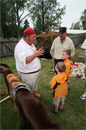 A tour guide in costume talks with two students.