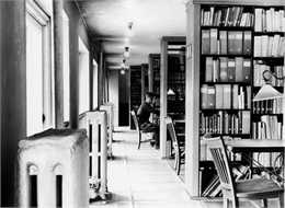 Young man studying at a table in the library stacks.