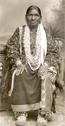 Studio portrait of a Winnebago woman posed in front of a painted backdrop.