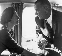 Lyndon Baines Johnson, the 36th President of the United States, is shown with his wife, Lady Bird Johnson, having an intense discussion, while seated in an airplane.