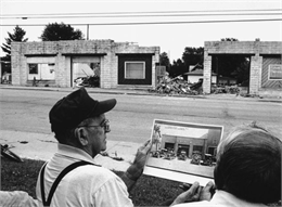 "Les Beck displays a 1930s photograph of the garage that is being displaced by the present-day Theresa Cwik Mart."