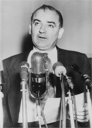 Joseph McCarthy speaking in front of multiple microphones about the clash between himself and President Eisenhower.