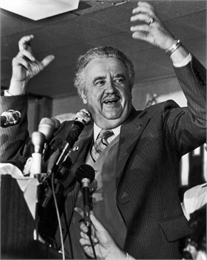 Lee Sherman Dreyfus lifts his arms skyward in triumph at a podium before his election supporters.