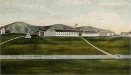 A view of Fort Crawford from the valley. A U.S. flag flies above the white hospital building.