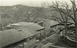 Elevated, exterior view of Taliesin, including a man in a horse-drawn carriage in the courtyard.