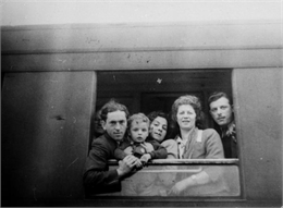 From left: unidentified man, son Andre, wife Rose, unidentified woman, Walter Wolf Peltz looking out of the window of a railroad car; Hamburg, Germany, en route to the United States.