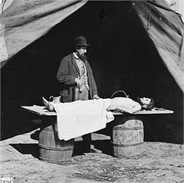 Embalming surgeon at work on soldier's body.