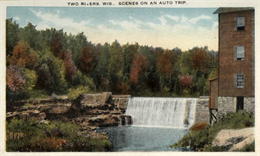 View of a dam surrounded by autumnal trees. The text on the postcard reads, "Two Rivers, Wis. Scenes on an Auto Trip."