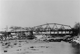 View of old bridge, river and buildings in downtown Black Falls River in the winter.