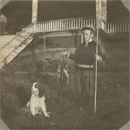 A young Aldo Leopold poses proudly with his bamboo fishing pole, stringer of fish and a dog.