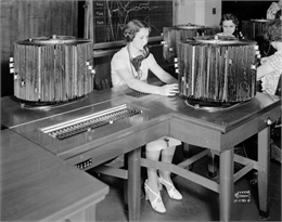 Women switchboard operators, wearing head sets with microphones.