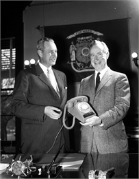 A man presents another man with the one millionth telephone sold in Wisconsin.
