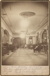 Interior view of lobby area of Newhall House hotel with several people sitting in chairs.