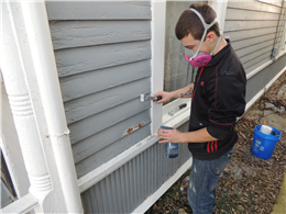 Image of someone misting the painted surface with water while scraping to reduce the amount of lead dust.