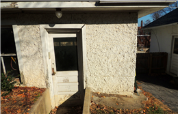 Image of stucco garage with concrete block foundation that has severely settled.