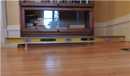 Image of a 4-foot level being used to determine how much the floor is sagging.