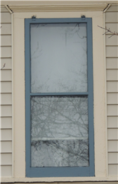 A well-maintained wooden storm window with metal storm hangers on top.