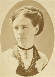 Studio portrait of young Clara Bewick Colby wearing a cross necklace.