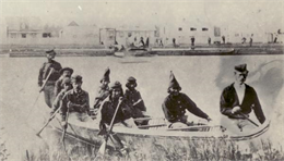 Nine men arrive at Fort William by canoe.