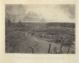 An empty battlefield with posts sticking out from an earthworks in the foreground.