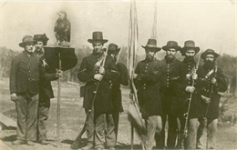 "Old Abe" and "Color Guard" of the Eighth Regiment, Wisconsin Volunteer Infantry, posed in uniform, outside with Old Abe on a shield perch.