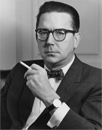 Reeves seated holding a cigarette.