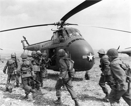 Black and white image of infantry troops boarding helicopters for Korea via the 6th Transportation Helicopter Company.