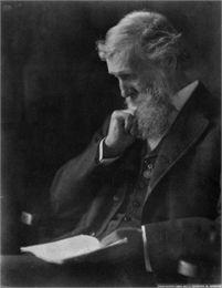 Photographic portrait of John Muir seated and reading a book.