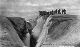 Photograph of a tourist group on Muir Glacier near a ravine.