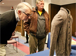 La Crosse County Historical Society board member Robert Mullen, left, inspects a sweater worn by Holocaust survivor "Ted" Kowalczyk while he was a prisoner at the Auschwitz concentration camp during World War II.