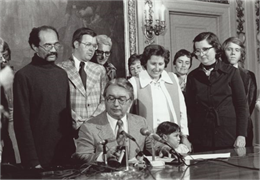 Several men and women watch as Governor Patrick Lucey signs the Equal Rights Amendment. Governor Lucey is seated at the desk in the middle.