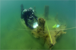 An underwater archaeologist dives to explore an submerged shipwreck.
