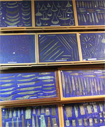 Copper artifacts from a personal collection displayed in frames on blue fabric.