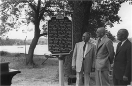 An image showing men standing near a historic marker about Ole Evinrude.