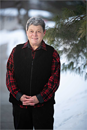 Photo of Peggy Marxsen wearing a black puffer vest and red and black plaid shirt.